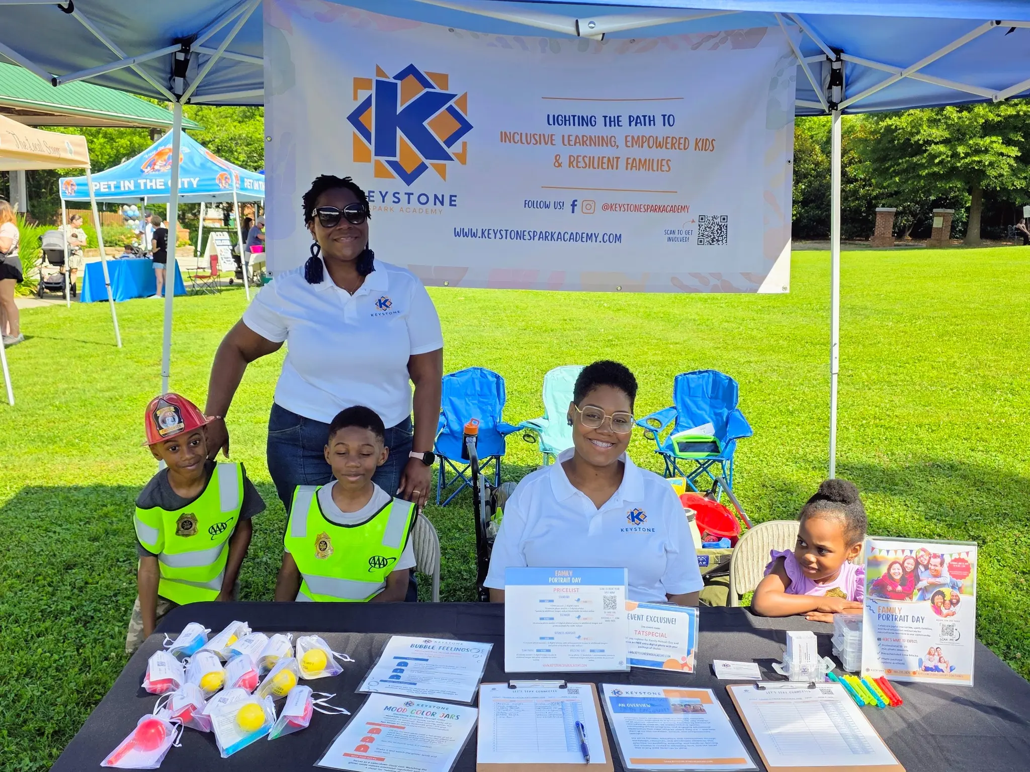 KSA team members and children welcoming visitors at a table with family activities and communication resources